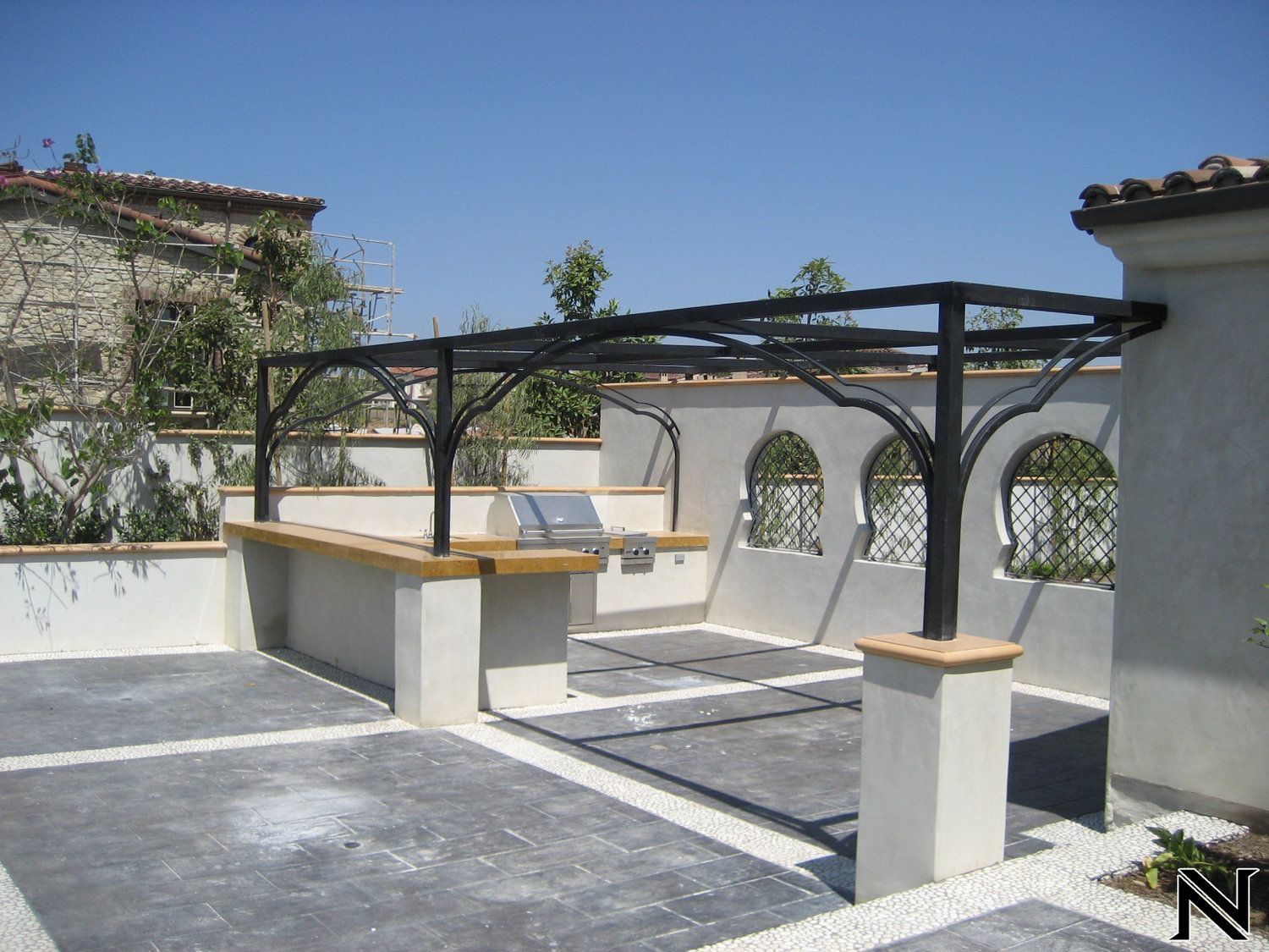 A patio with a grill and a pergola with the letter n on it