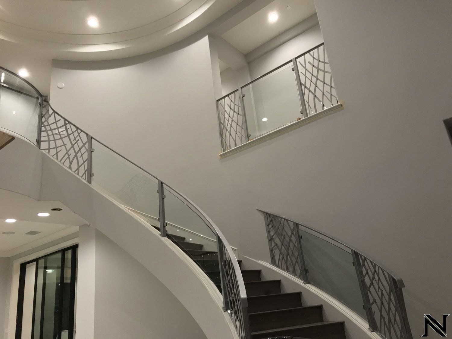 A curved staircase with a glass railing in a house