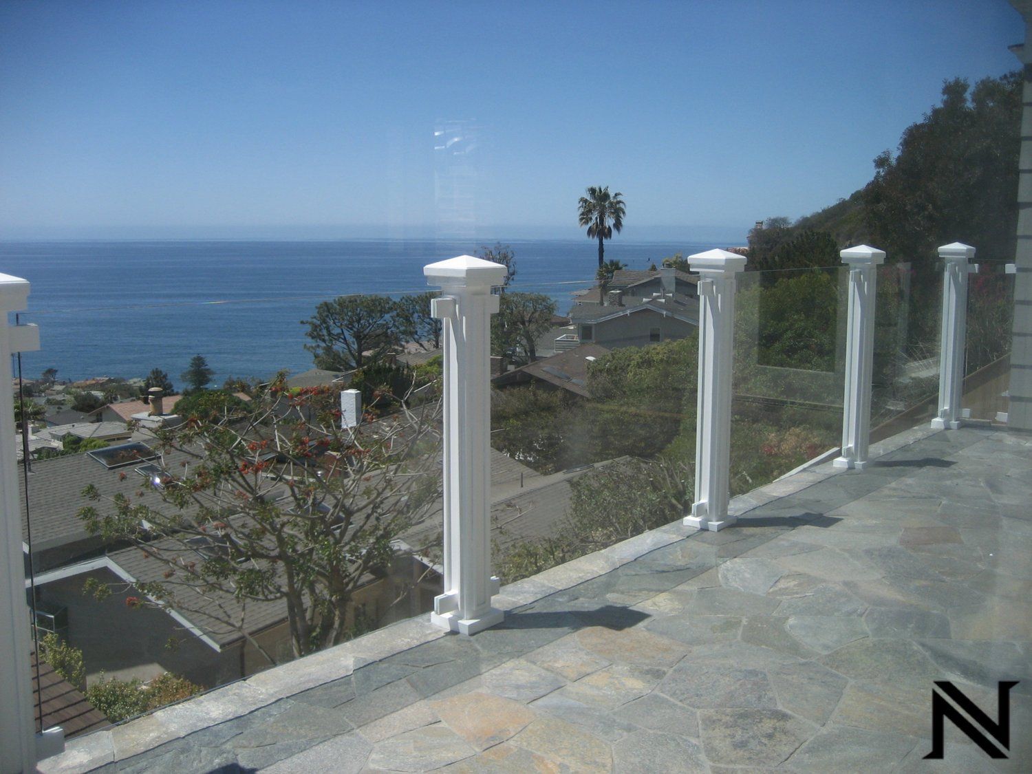 A view of the ocean from a balcony with the letter n in the corner