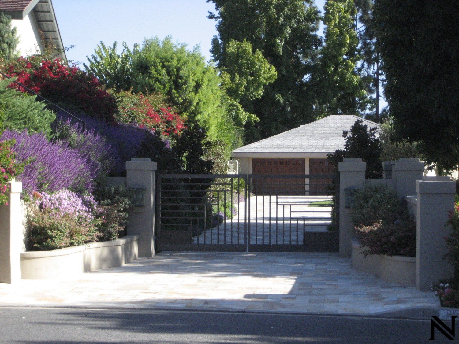 A driveway with a gate that has the letter n on it