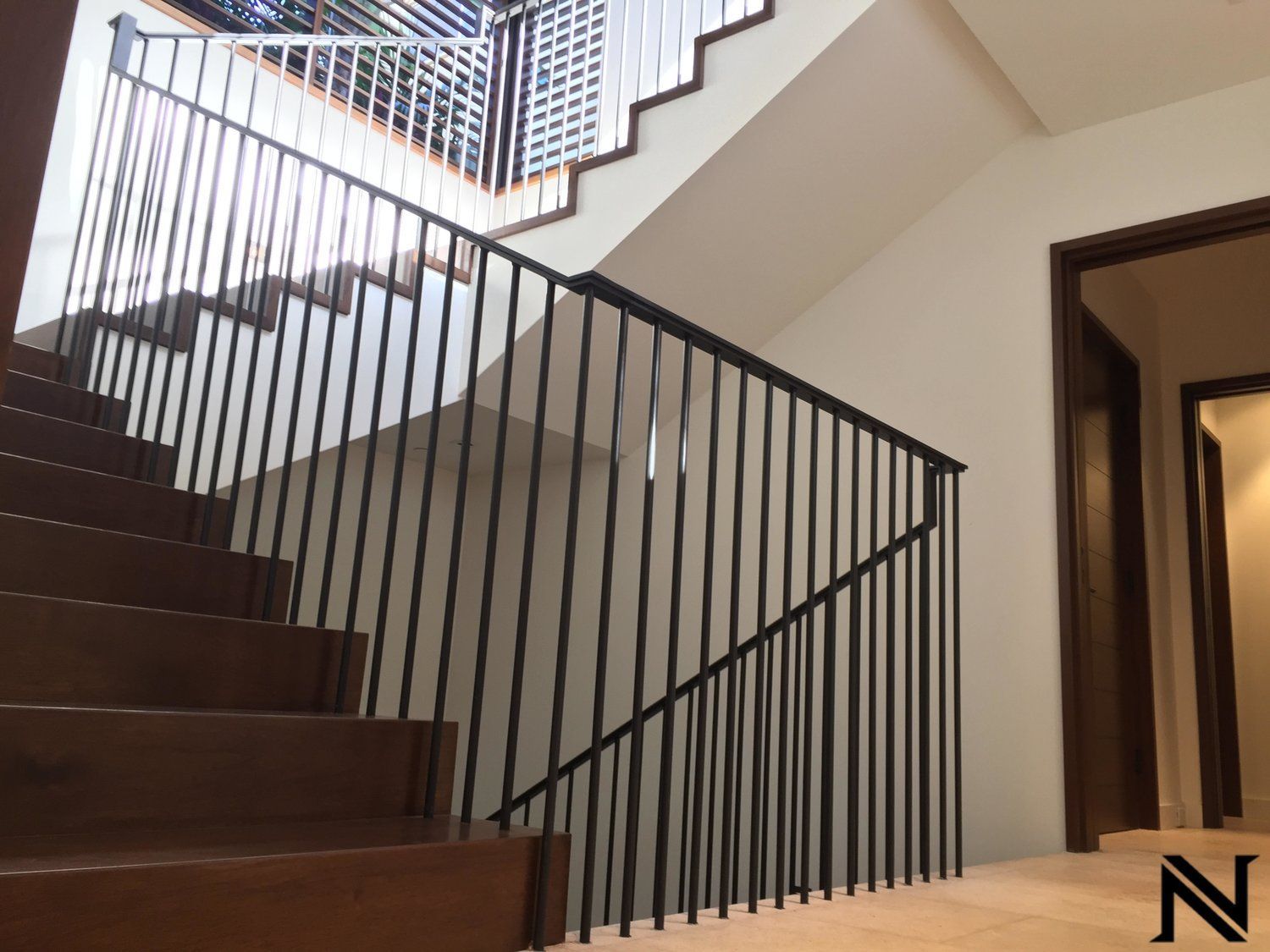 A staircase with a black railing and the letter n on the floor