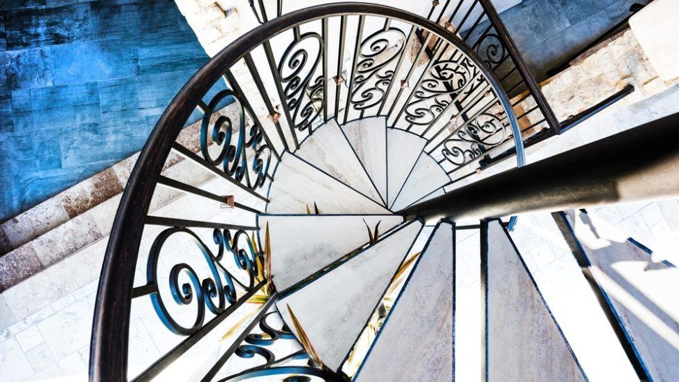 Looking up at a spiral staircase with a wrought iron railing.