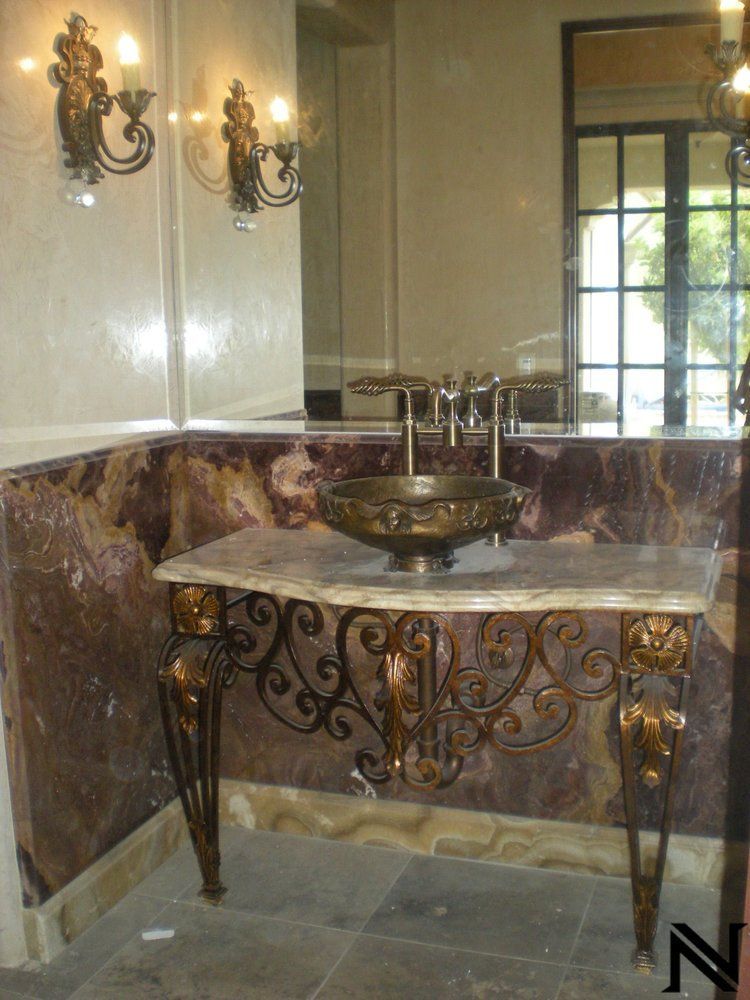 A bathroom with a marble counter top and a brass sink