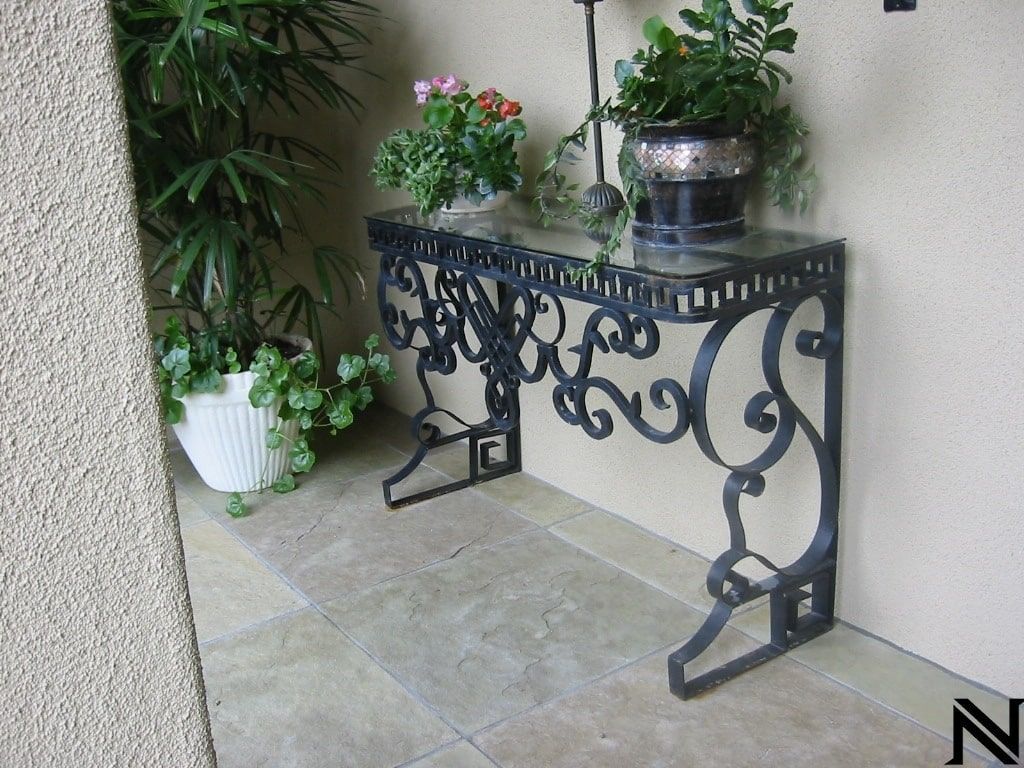 A wrought iron table with potted plants on it