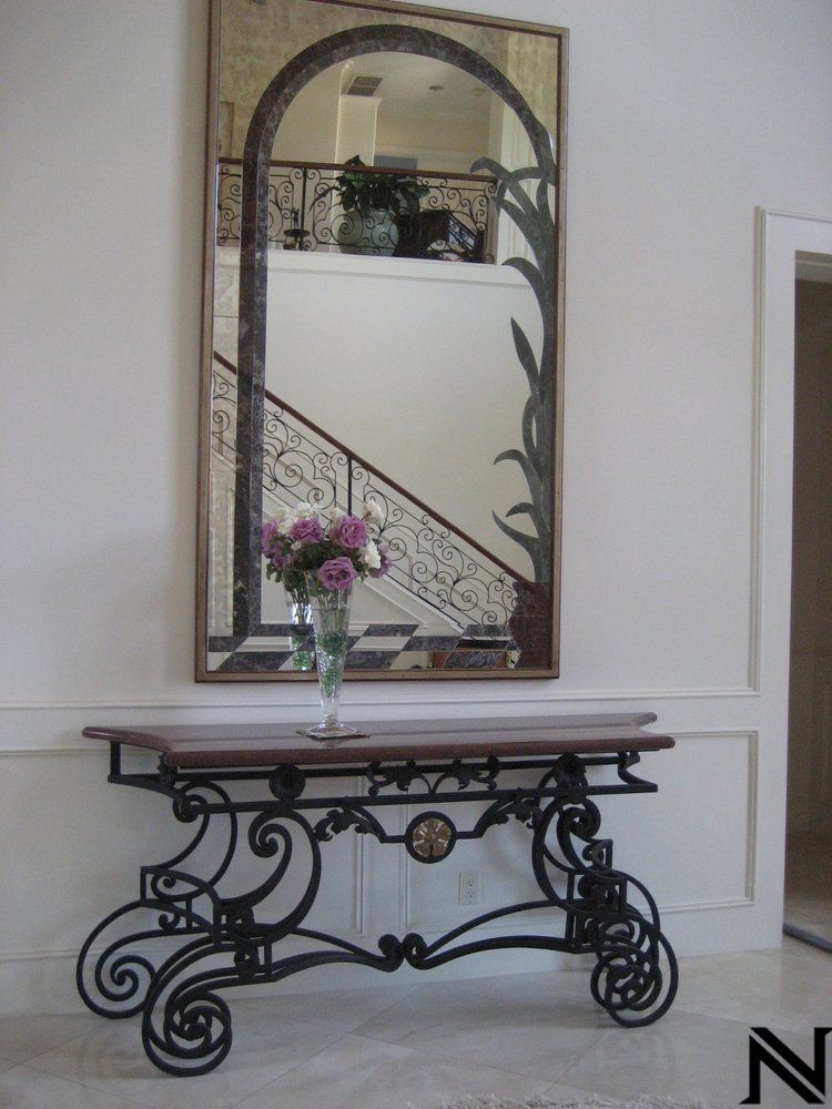 A large mirror hangs above a table with a vase of flowers on it