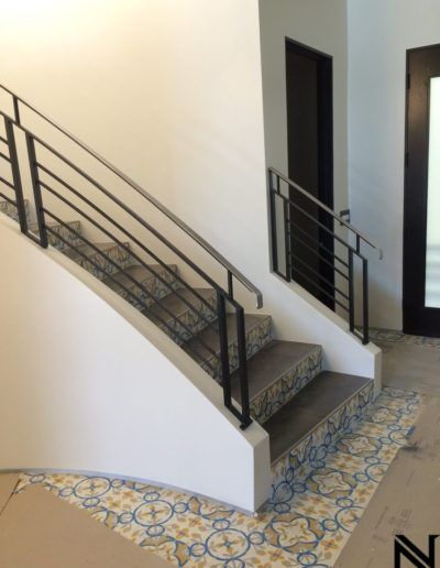 A staircase with a black railing and a tiled floor
