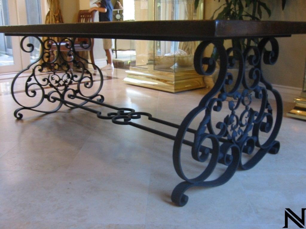 A table with a wrought iron base and a wooden top