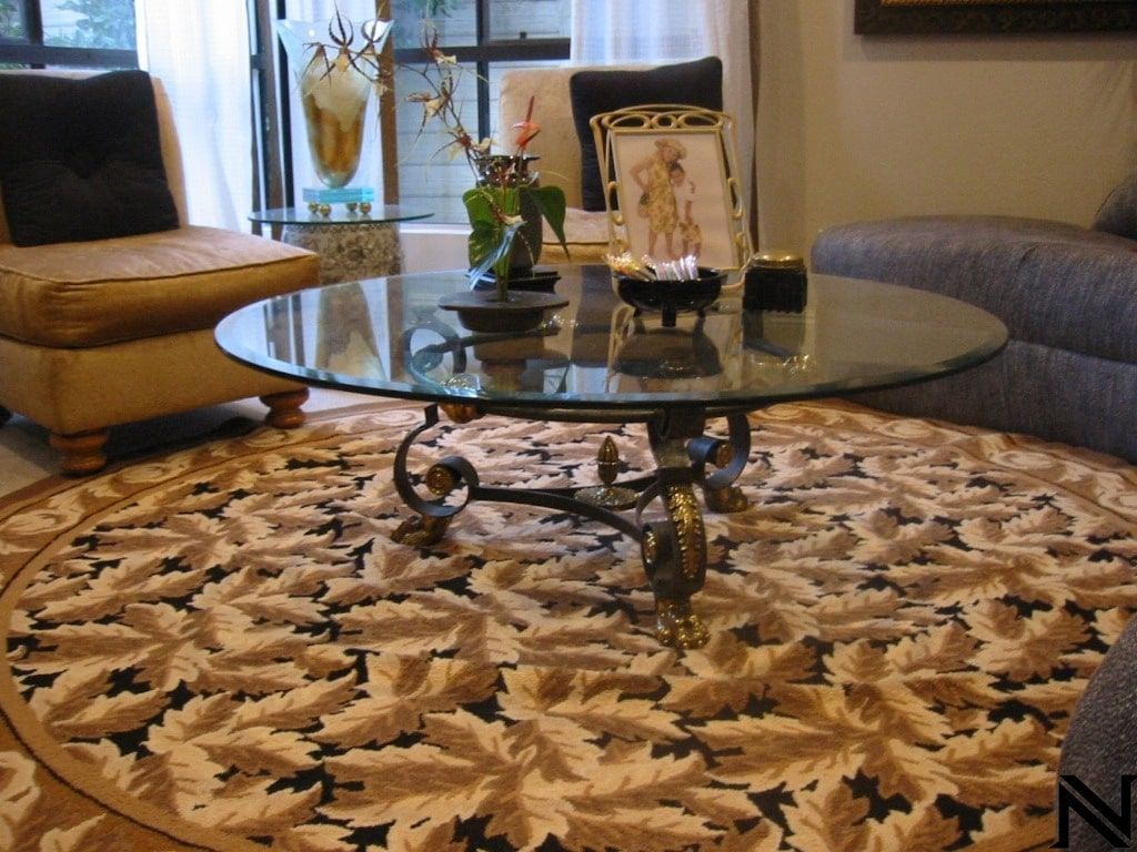 A living room with a round rug and a glass coffee table