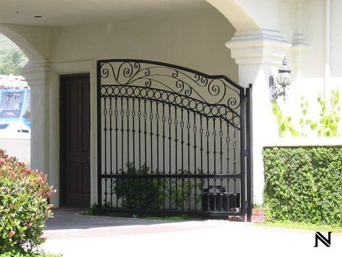 A black wrought iron gate is in front of a white house