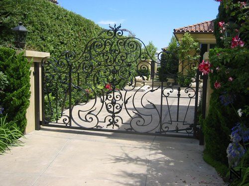A wrought iron gate is open to a driveway