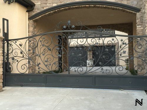 A wrought iron gate is in front of a house.