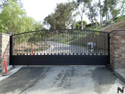 A black gate is closed on the side of a road