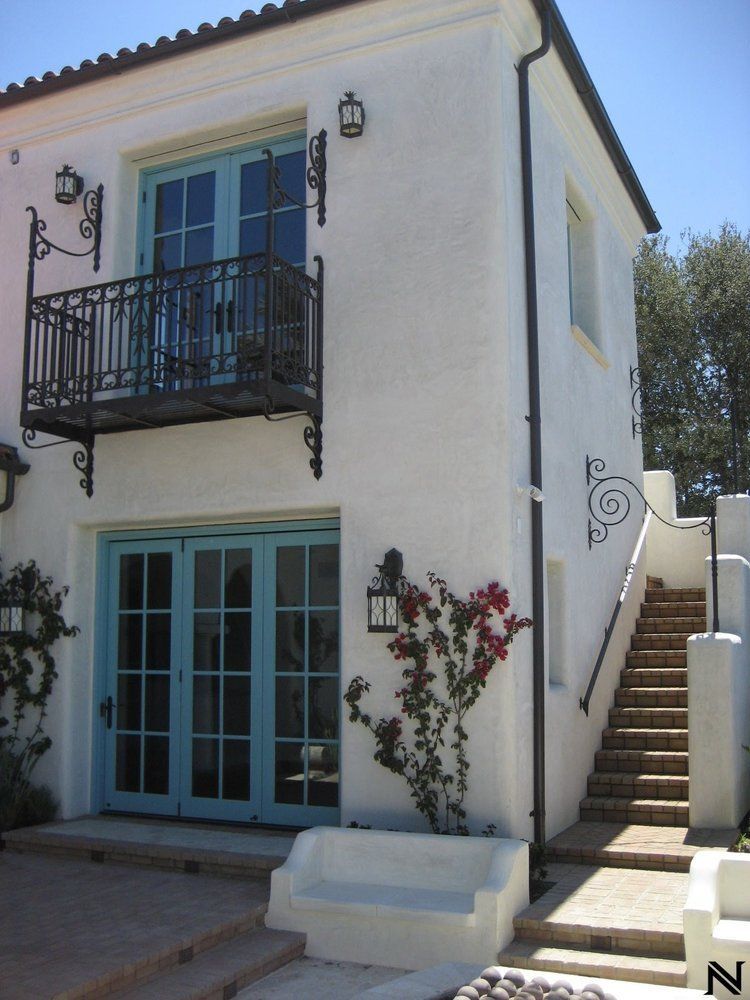 A white house with blue sliding glass doors and stairs