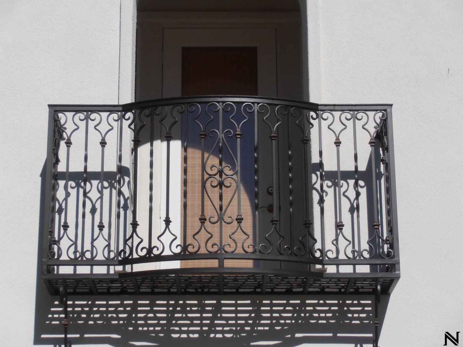 A balcony with a wrought iron railing on a white building