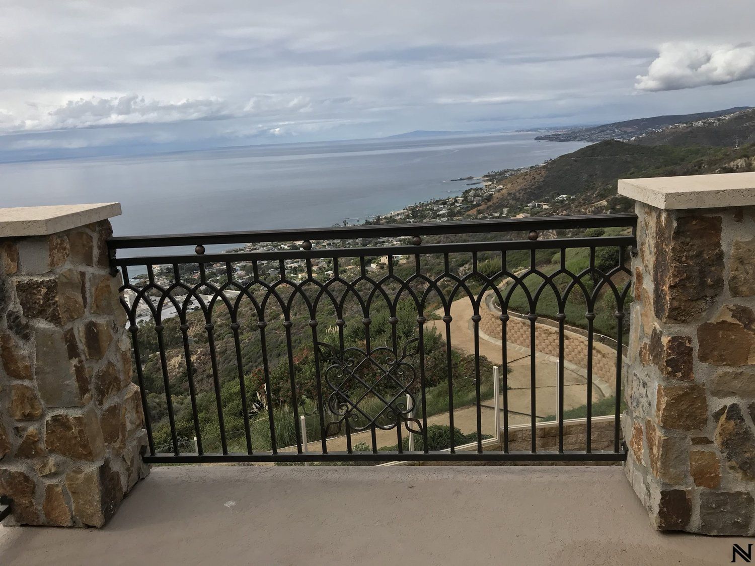 A balcony with a view of the ocean and mountains