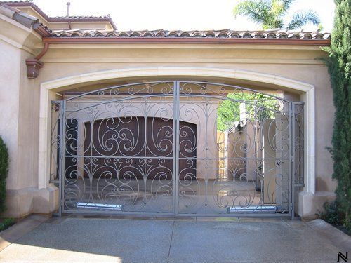 A wrought iron gate is open in front of a house