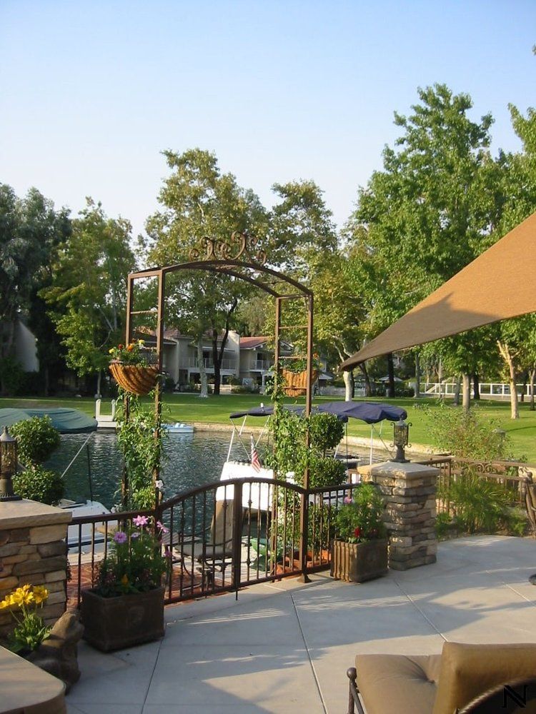A patio with a large umbrella and a boat in the background