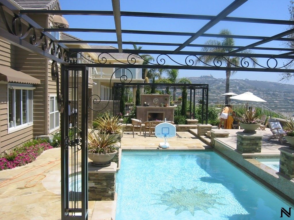 A large swimming pool is surrounded by a pergola with the letter n on it