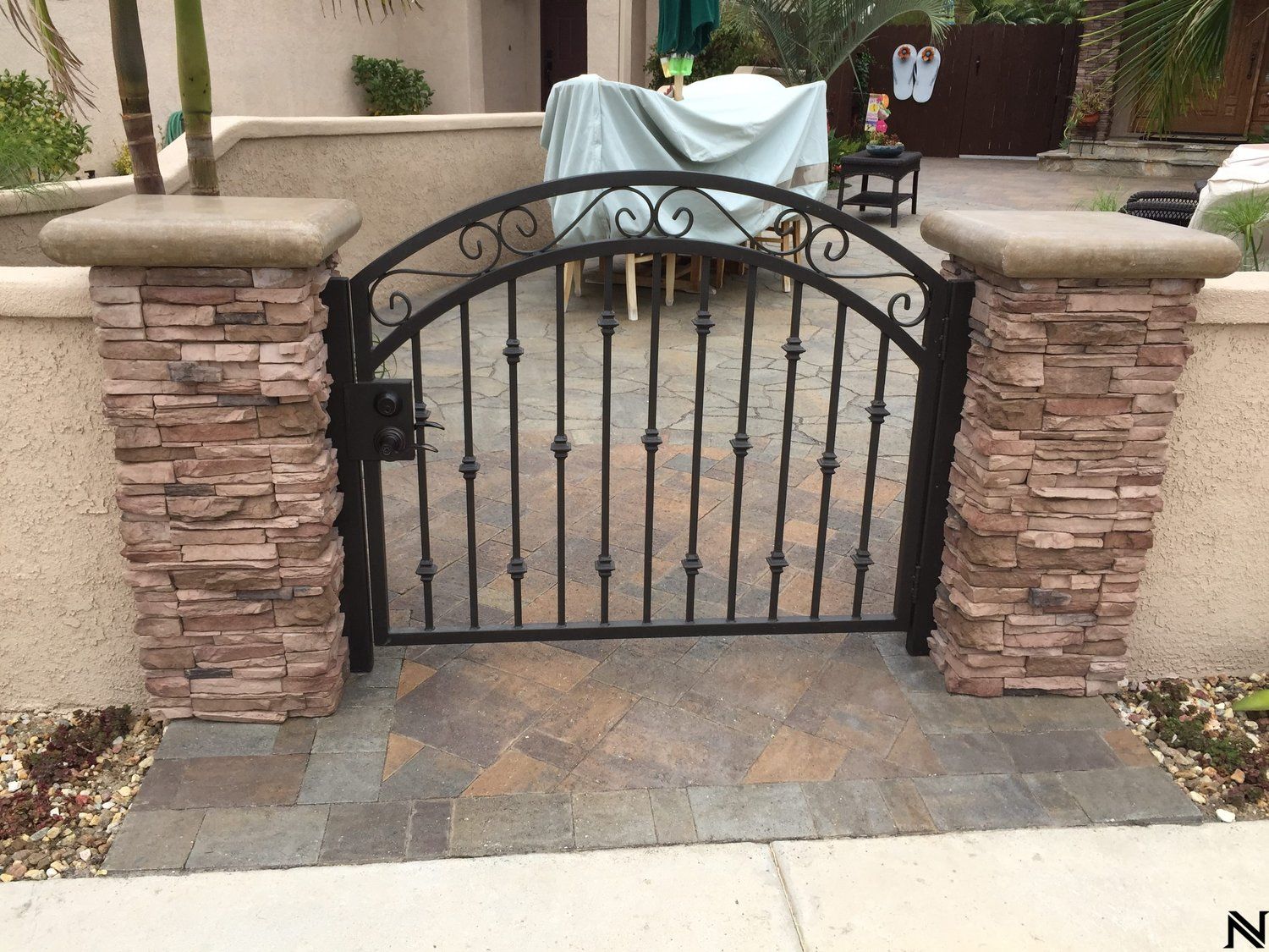 A wrought iron gate is surrounded by stone pillars.