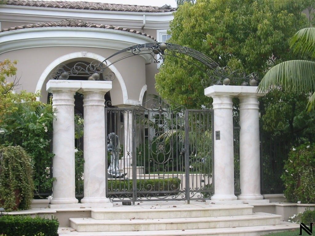A gated entrance to a house with columns and a gate