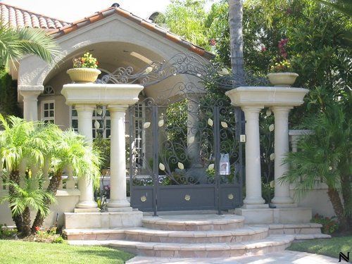 A gated entrance to a house with columns and stairs