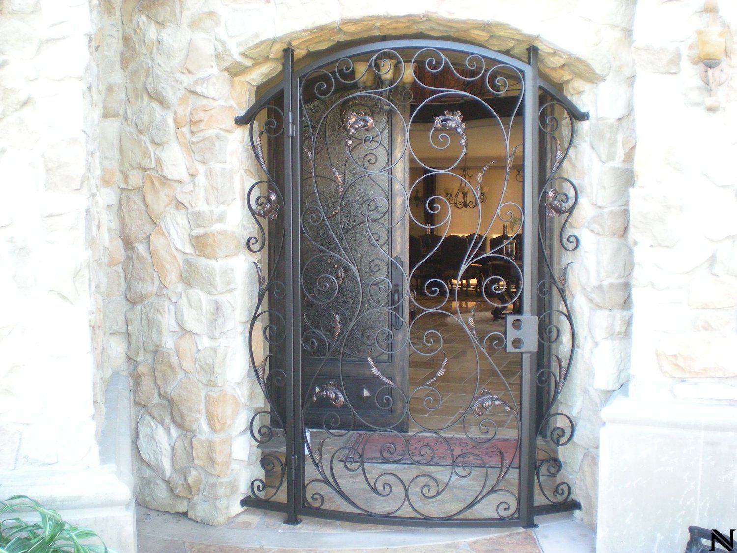 A wrought iron gate is in front of a stone wall.