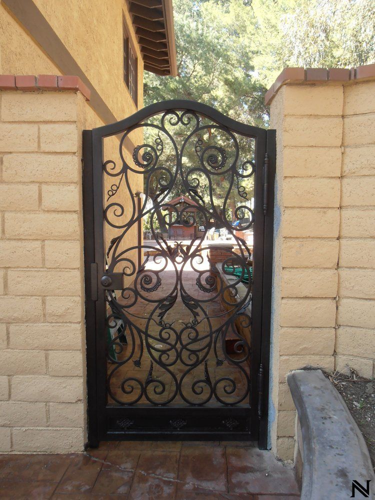 A wrought iron gate in front of a brick wall