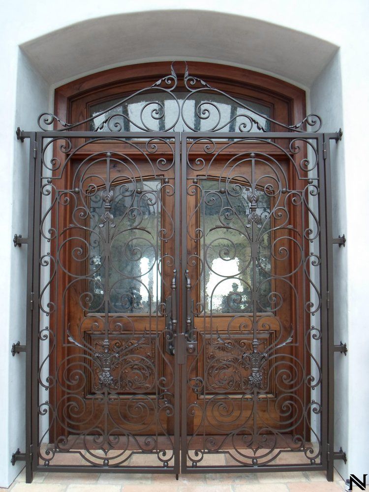 A wrought iron gate surrounds a wooden door