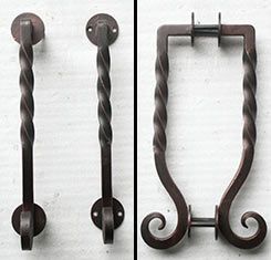 A pair of wrought iron door handles on a white wall.