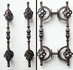 A close up of a wrought iron door handle on a white surface.