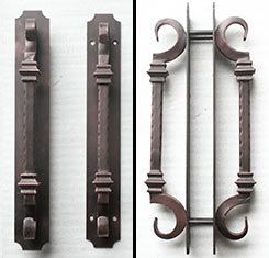 A pair of wrought iron door handles on a white surface.