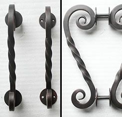 A close up of a wrought iron door handle on a white surface.