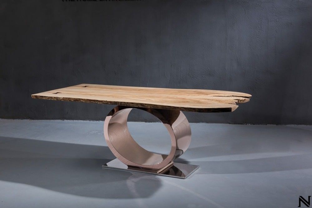A wooden table with a circular base is sitting on a concrete floor.