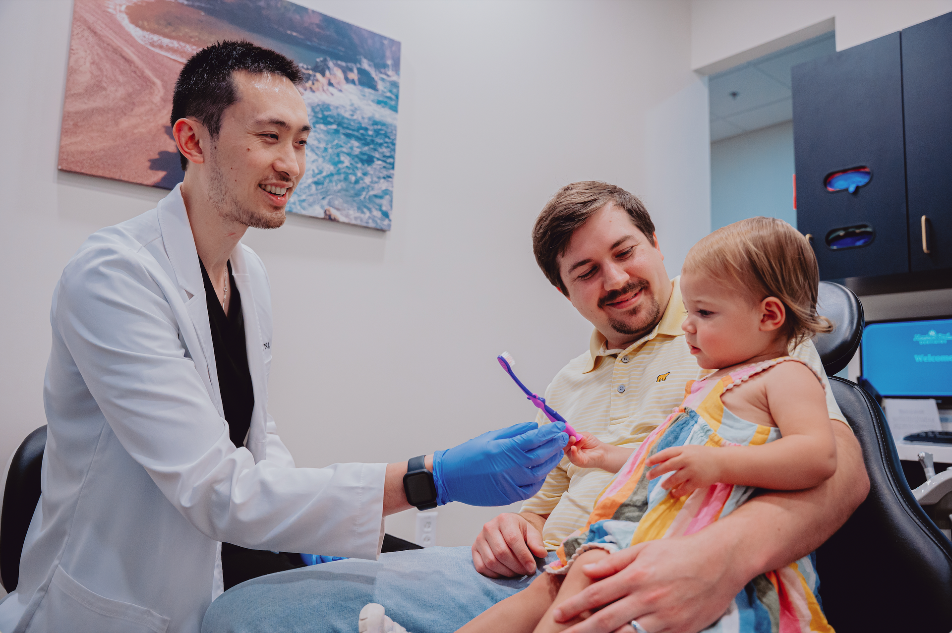 A little boy is sitting in a dental chair while a dentist examines his teeth.