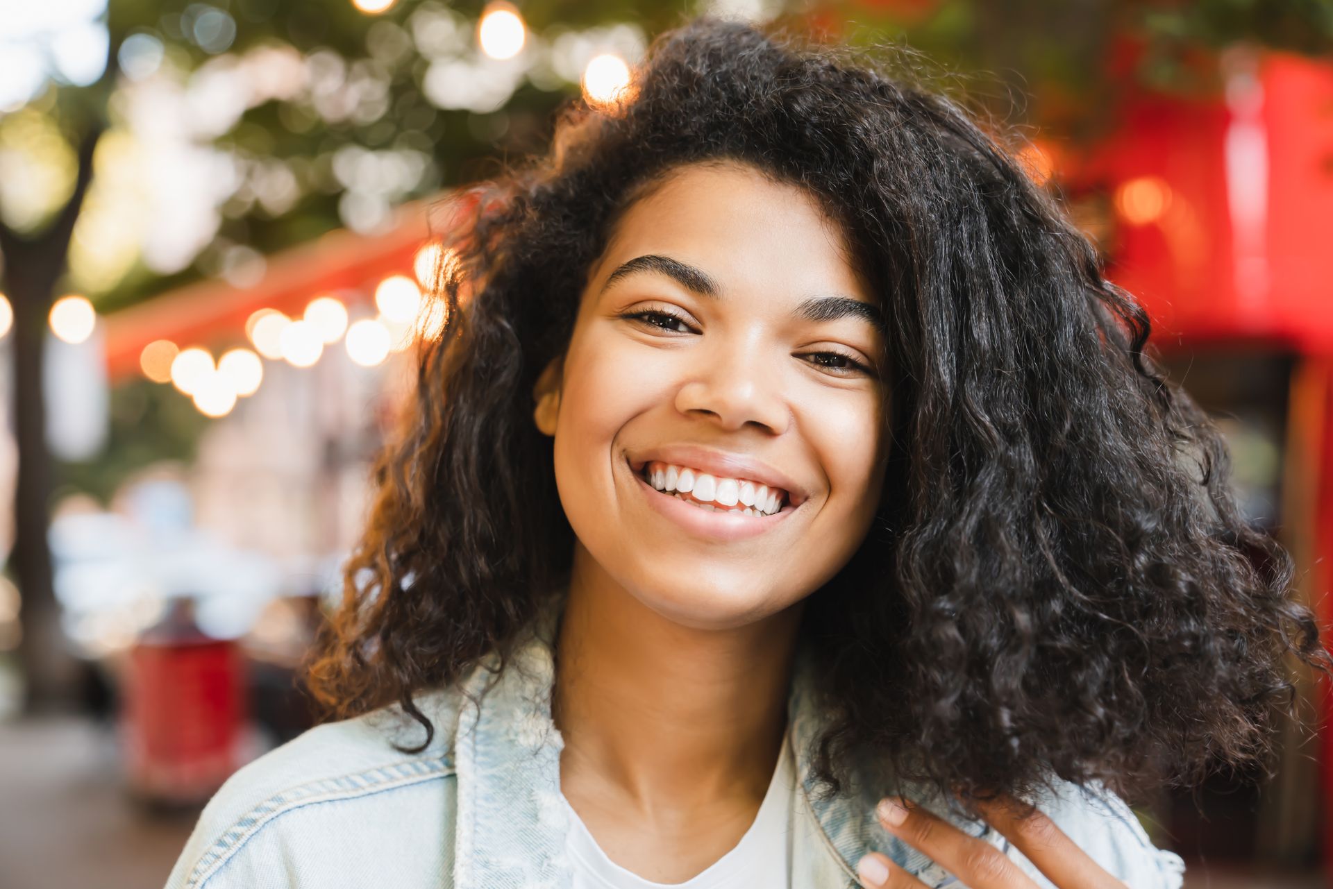 A woman with curly hair is smiling and looking at the camera.