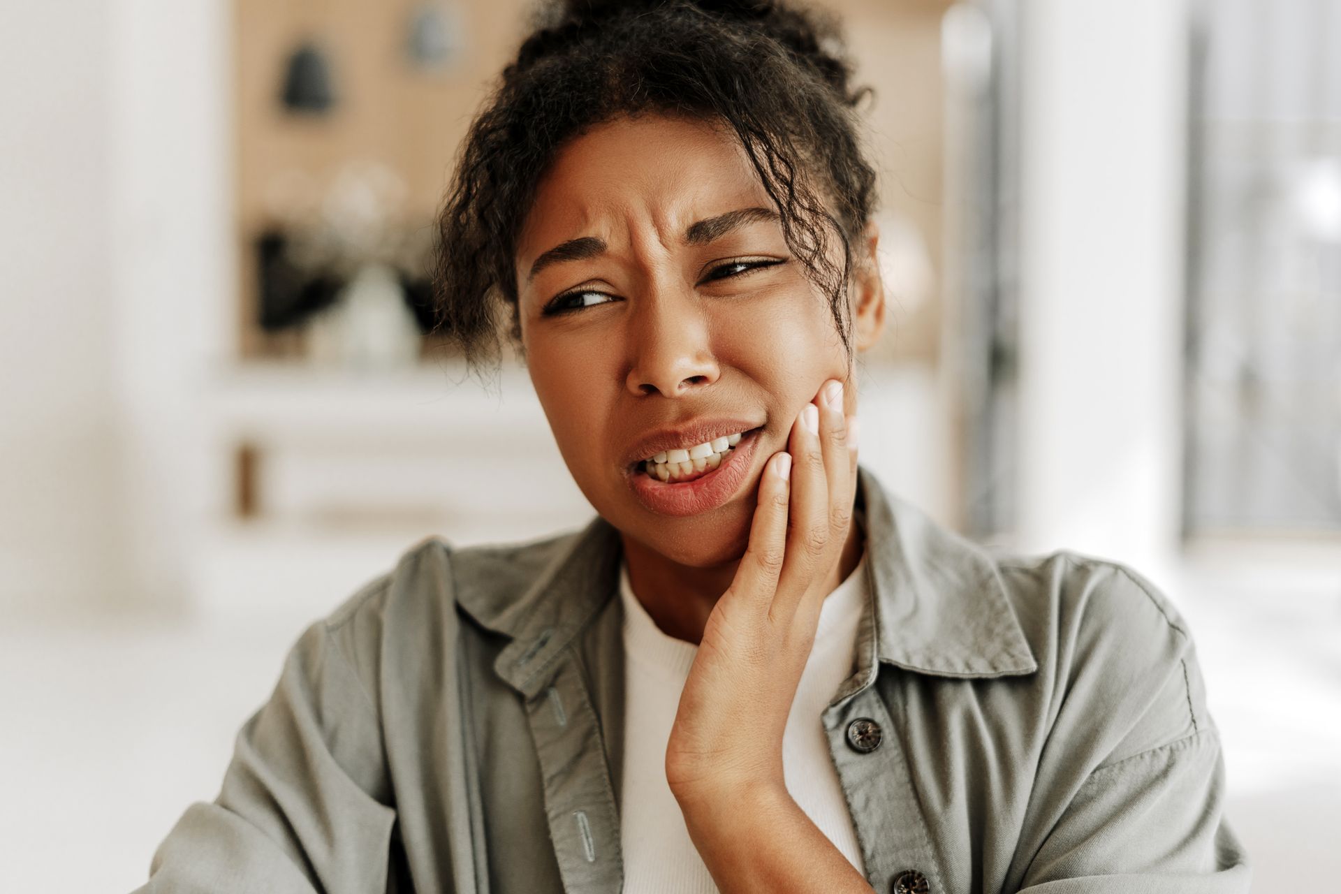 A woman is holding her face in pain because of a toothache.