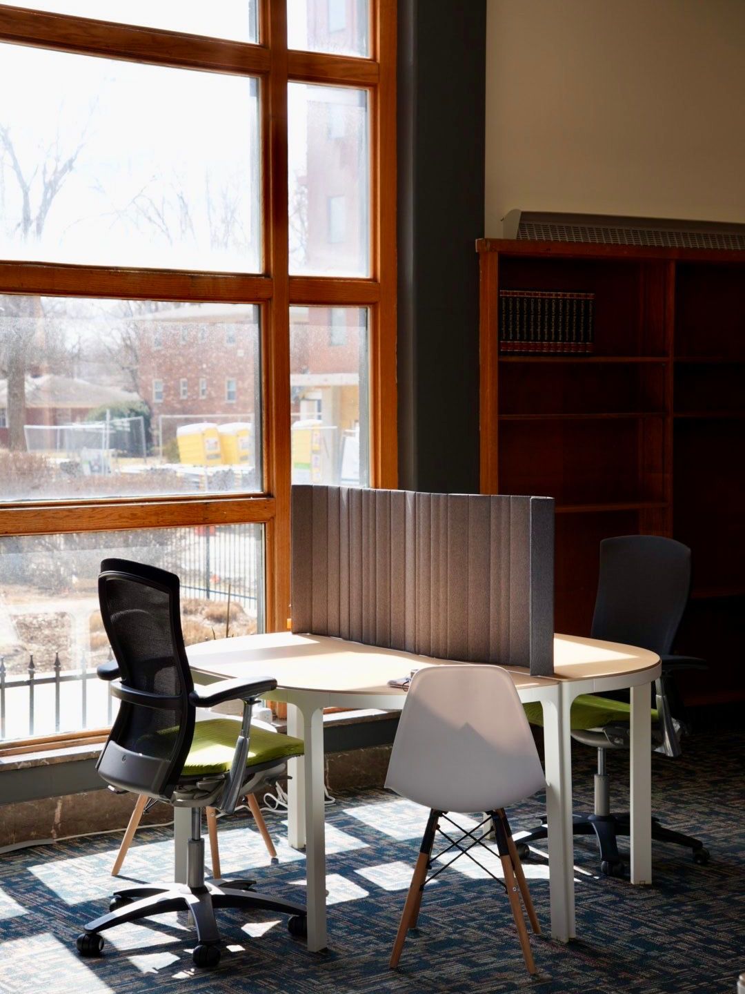 A living room with a black couch , chair , table and bookshelf.