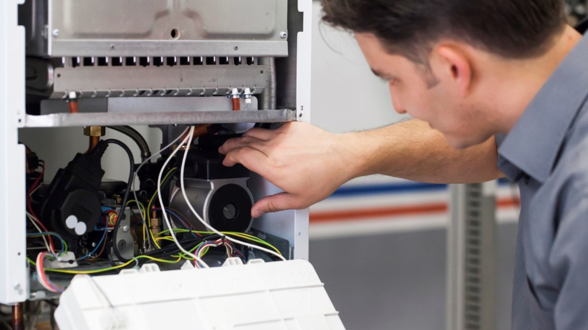A man is working on a boiler in a factory.