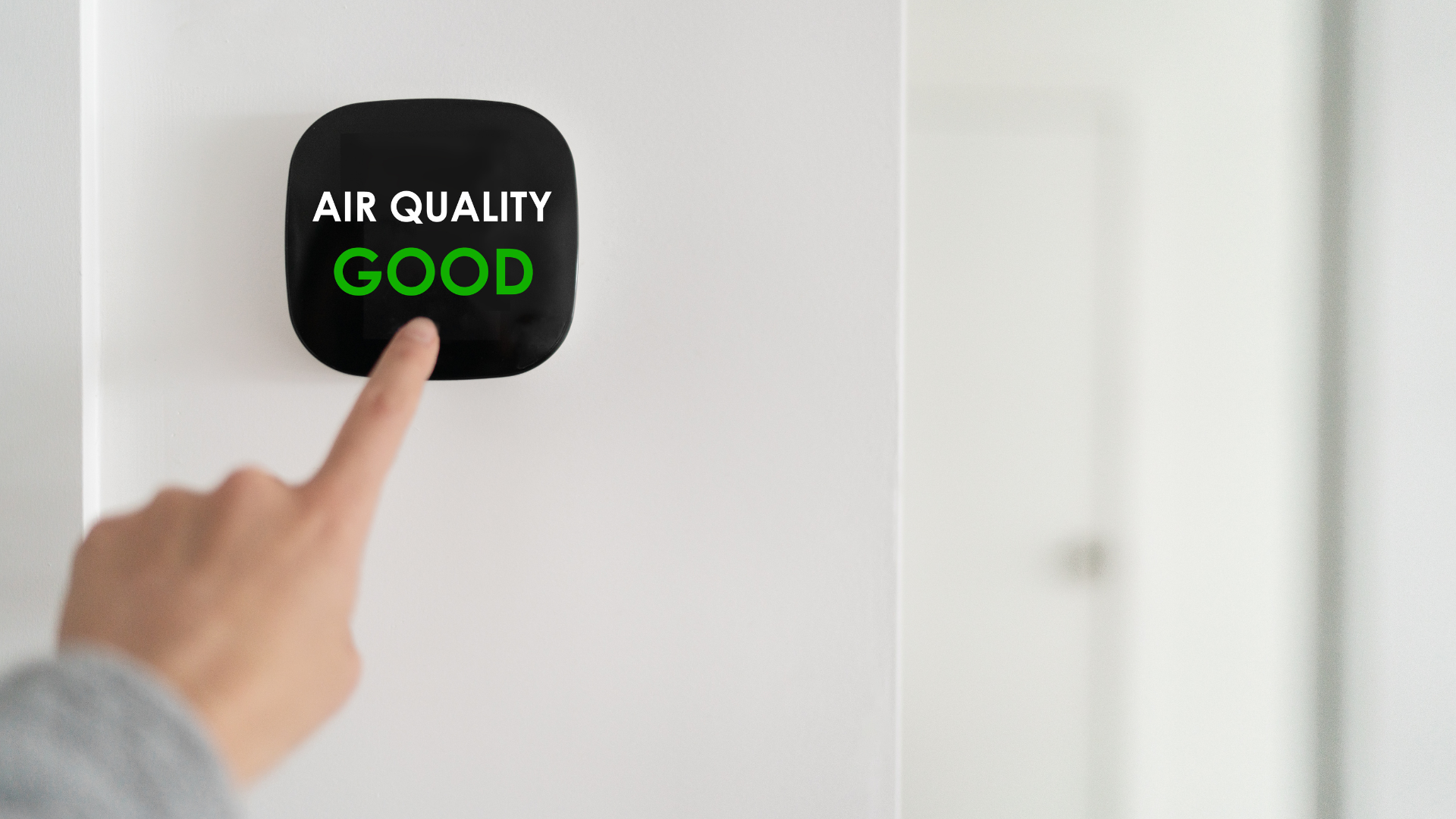 A person is pressing a button on a wall that says `` air quality good ''.