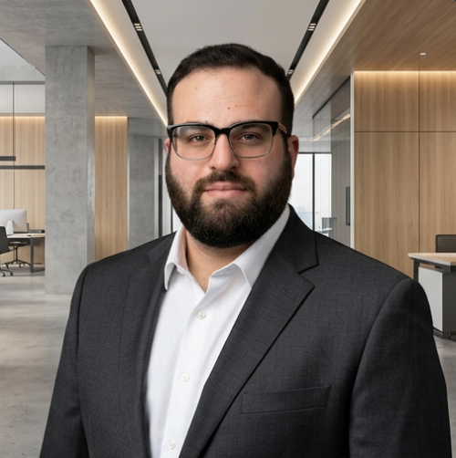 Man in glasses and suit, smiling in an office setting.
