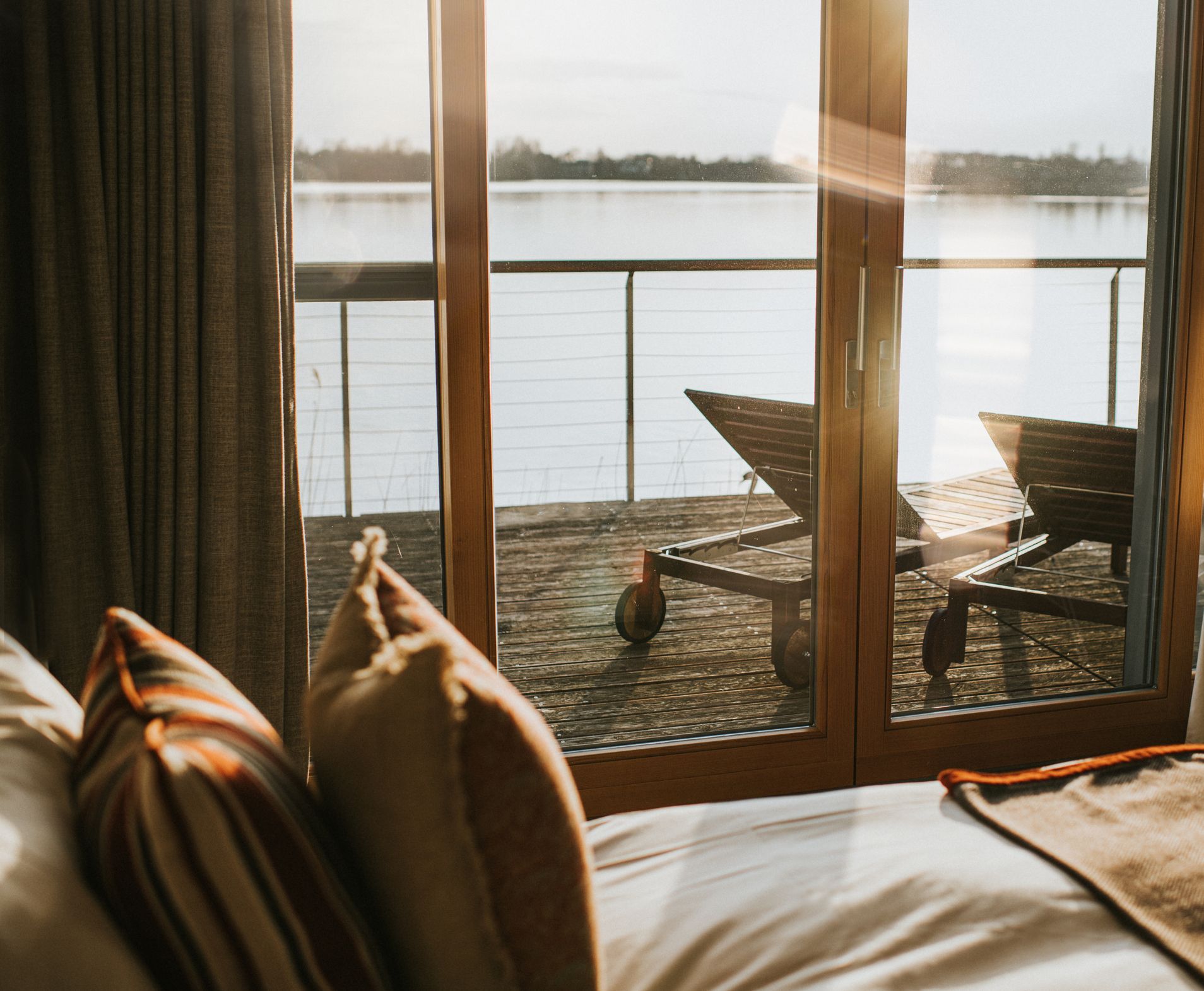 A bedroom with a view of a lake through a sliding glass door.