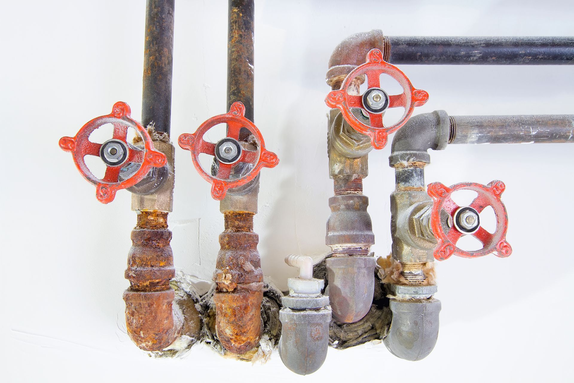 A bunch of rusty pipes with red handles on them.