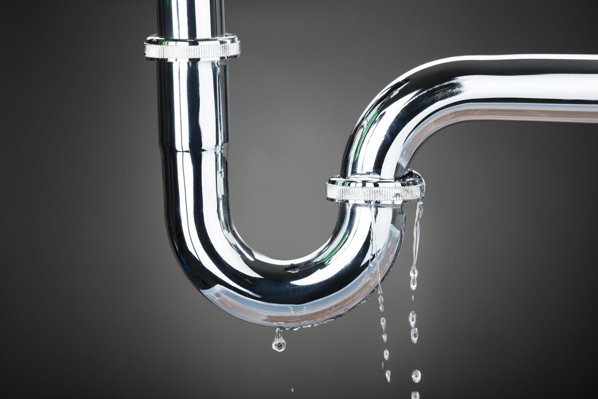 A close up of a drain pipe with water leaking out of it.