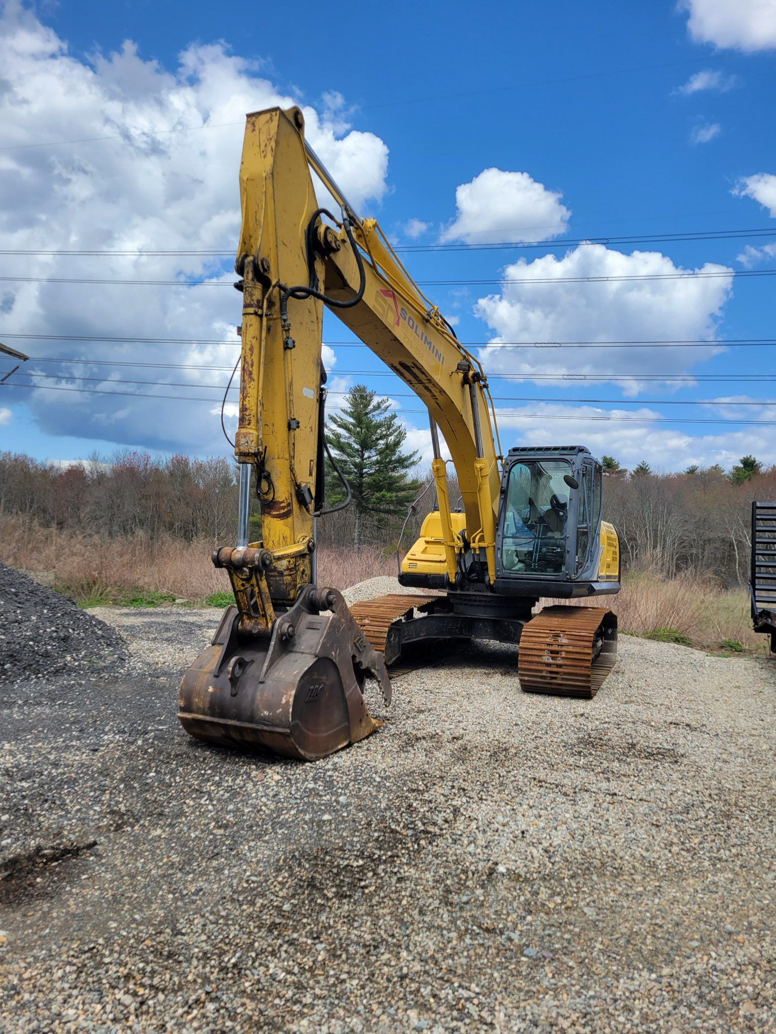 A yellow excavator is parked in a gravel lot.