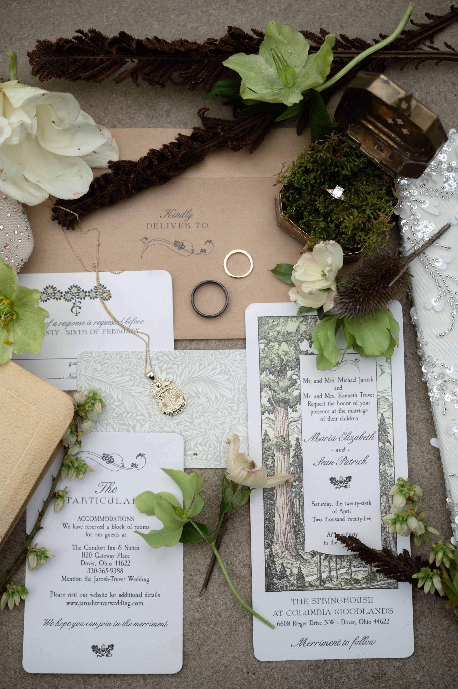 A wedding invitation is sitting on top of a table next to a ring and flowers.