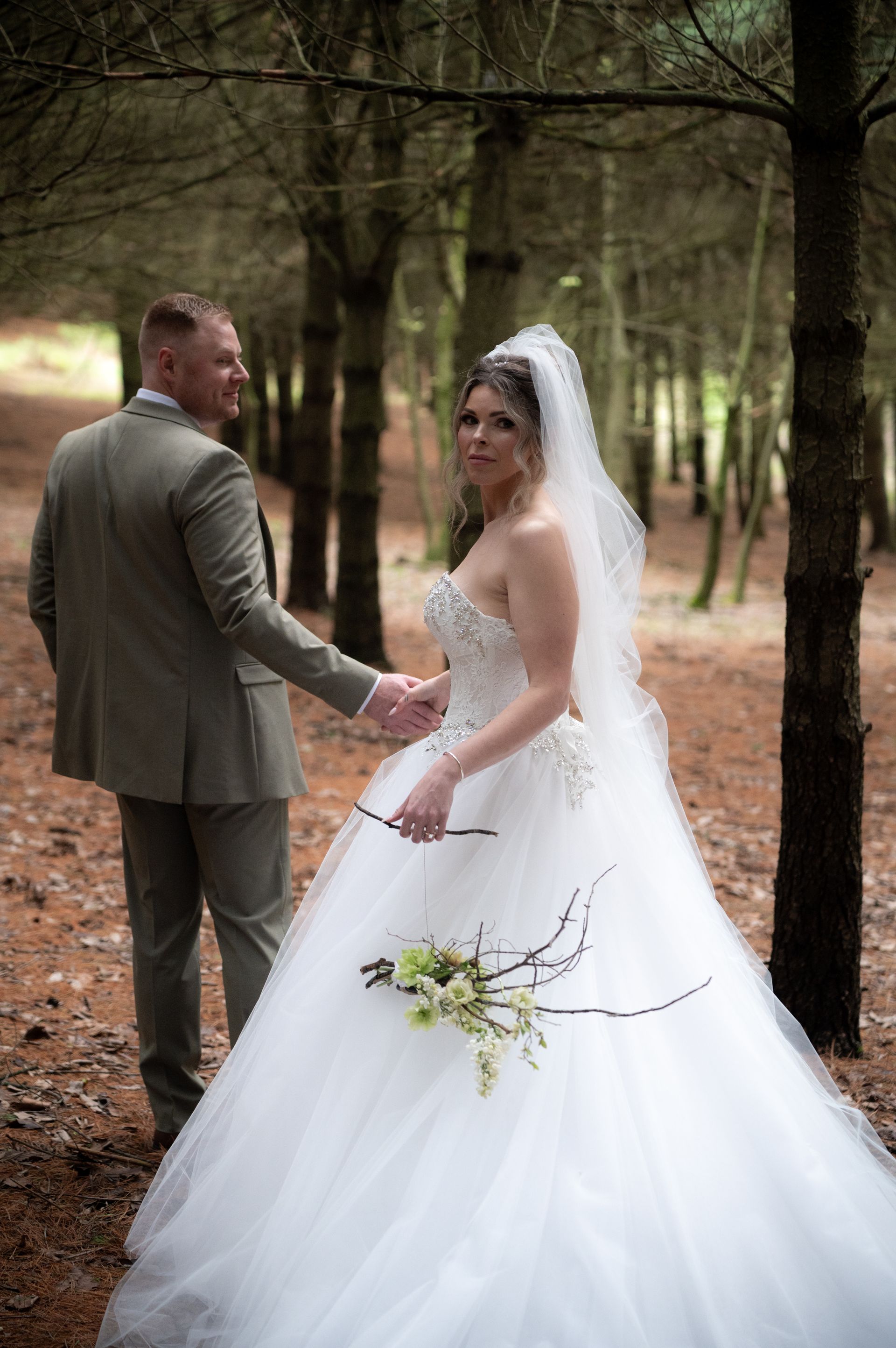 A bride and groom are holding hands in the woods.