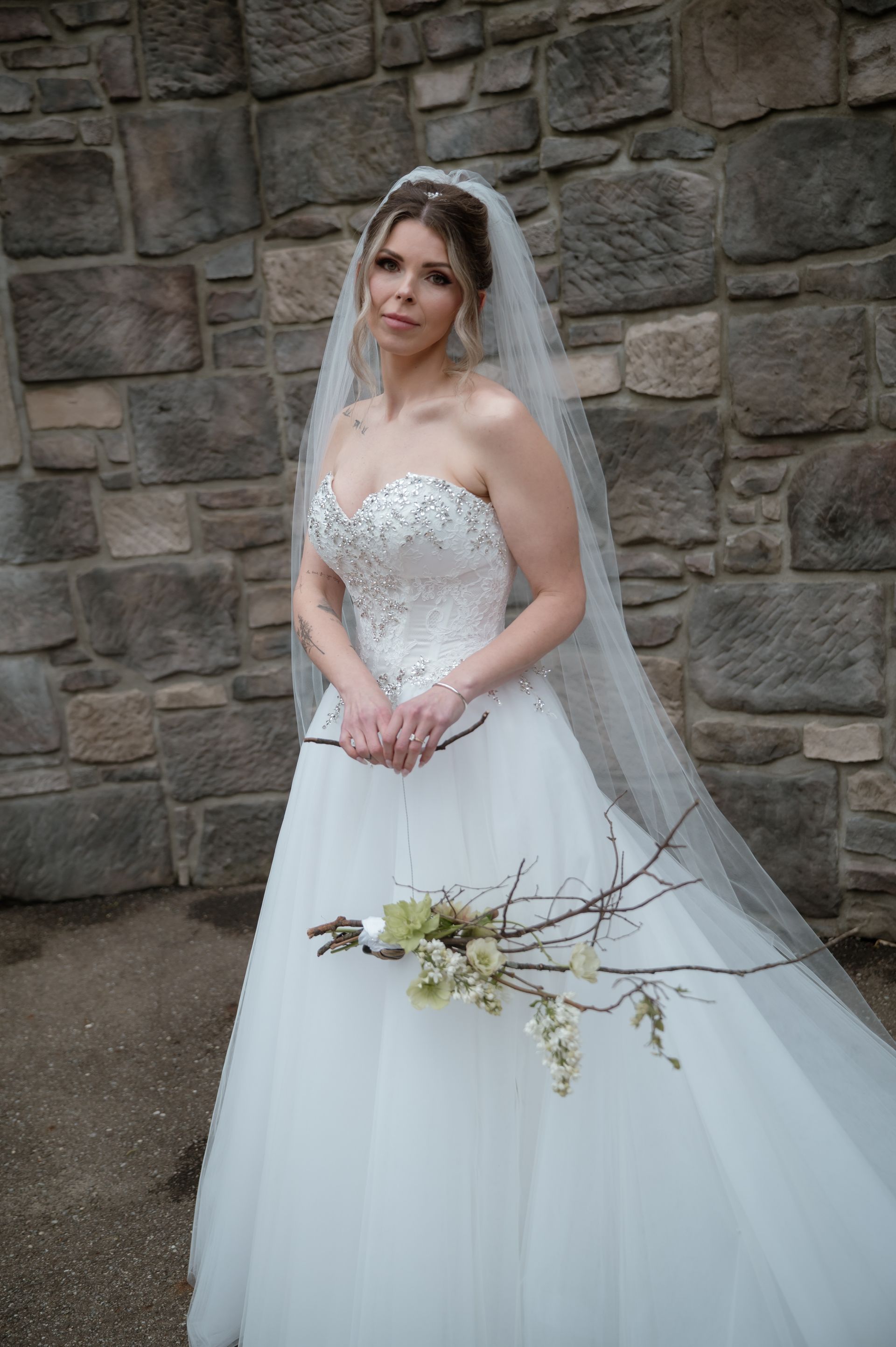 A bride in a wedding dress and veil is holding a bouquet of flowers.