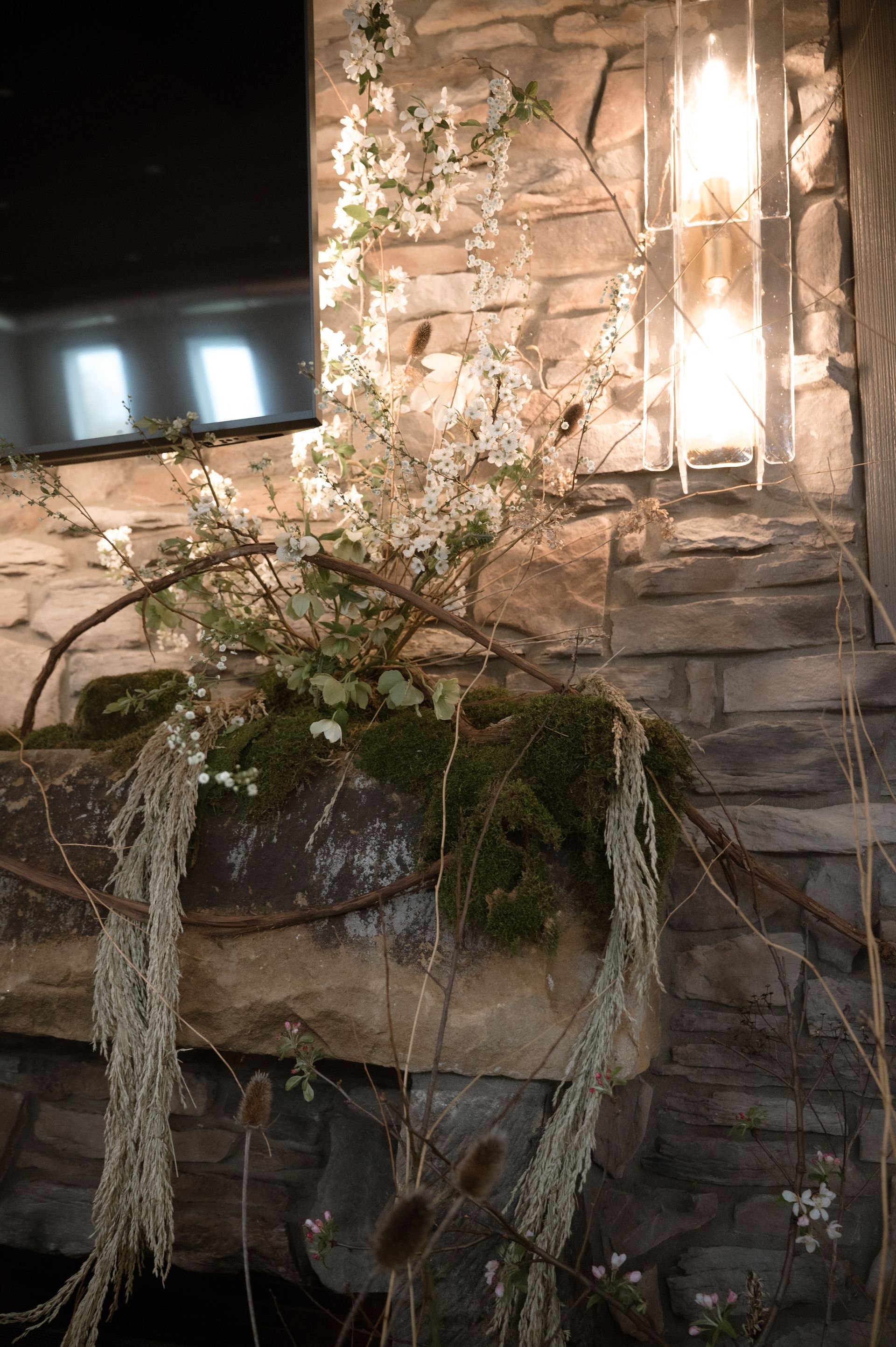 A fireplace with flowers and a lantern on it