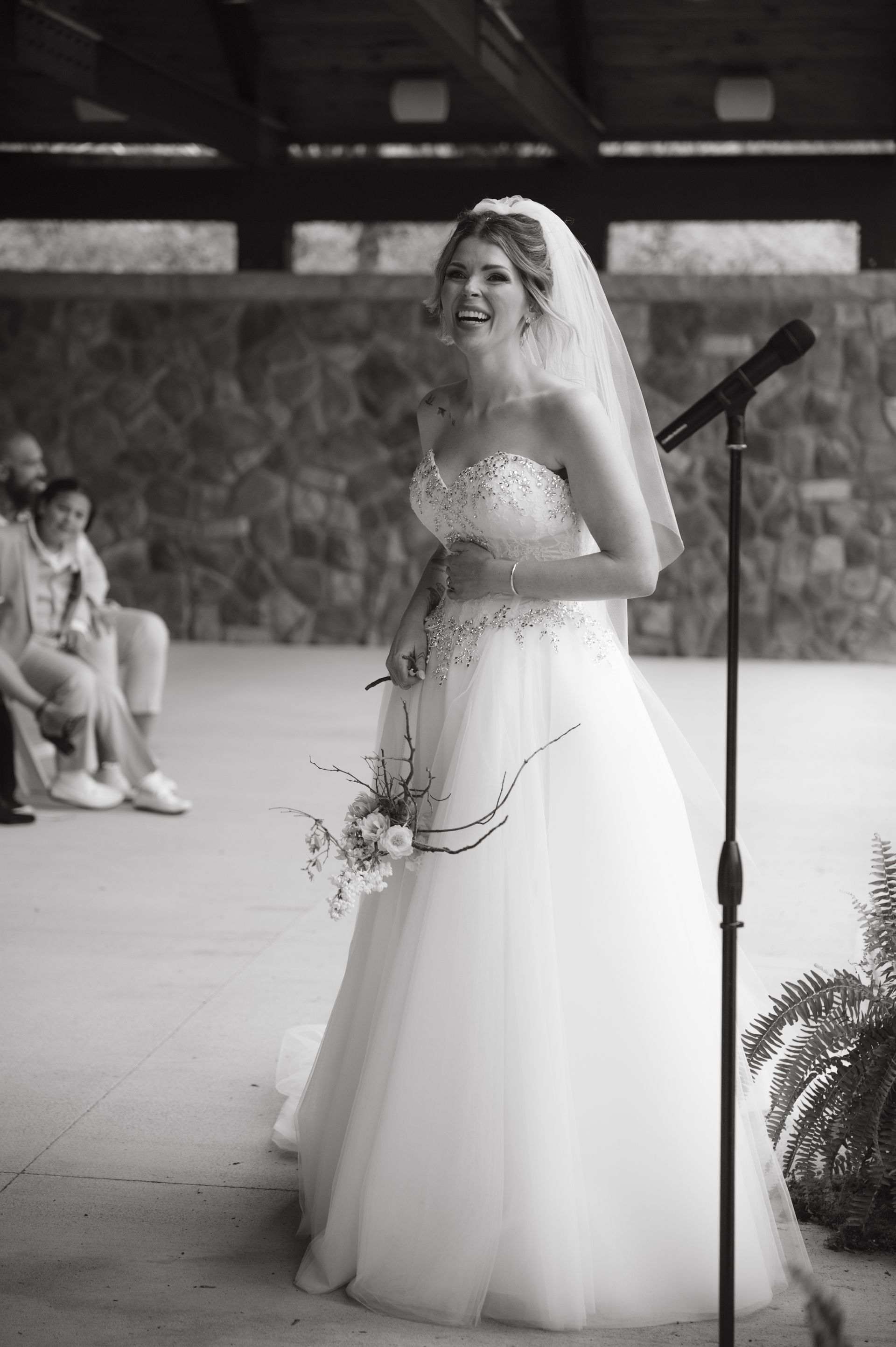 A bride in a wedding dress is standing in front of a microphone.