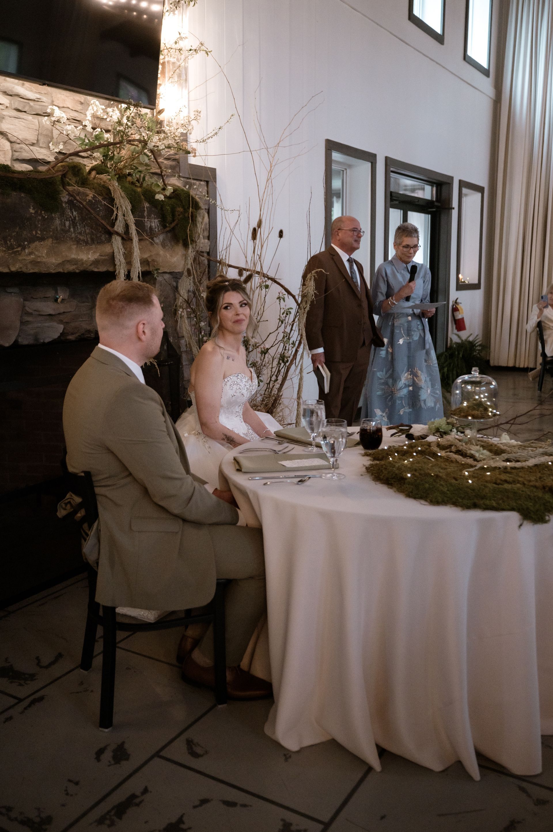 A bride and groom are sitting at a table at a wedding reception.
